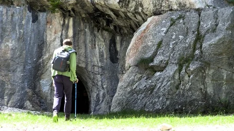 Young hiker exploring cave with carved entrance in summer day Stock Footage 102807339