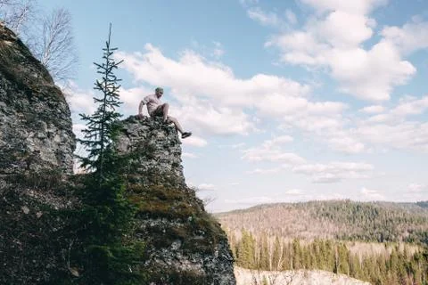 Young hiker looking down from a top of a mountain Stock Photos