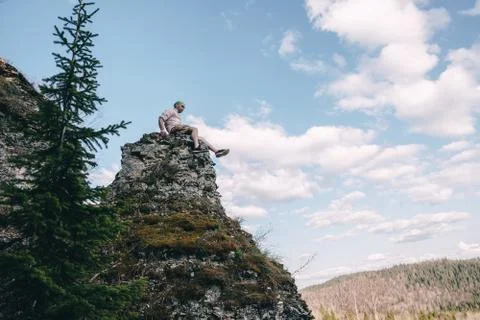 Young hiker looking down from a top of a mountain Stock Photos
