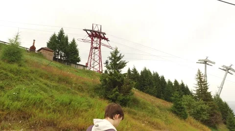 Young hiker on a mountaintop with modern cable car Stock Footage 68418608