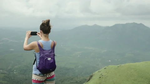Young hiker taking a photo from top of moutnain with smartphone Stock Footage 59679455
