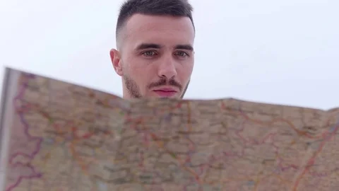 Young, hiking man with map looking for direction in autumn forest 動画素材 77799072