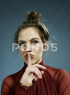 A young hip woman with her index finger on her lips, thinking Stock Photos