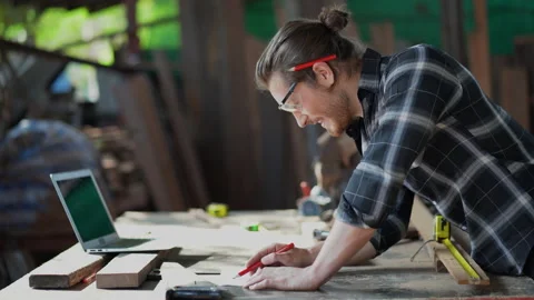 Young hipster carpenter man working with computer laptop in workshop . crafts Stock Footage 149983895
