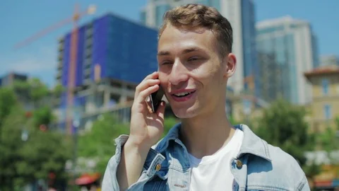 Young hipster in denim jacket holds smartphone and talks Stock Footage 113798347