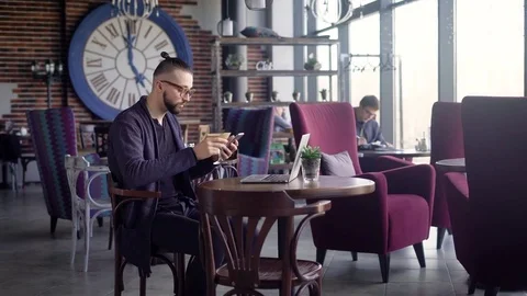 A young hipster drinks a cocktail while sitting at a wooden table in a Stock-Footage 75488952