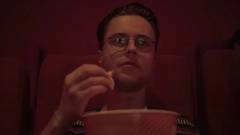 A young hipster eating popcorn while watching the premiere of a motion picture Stock-Footage 80254813