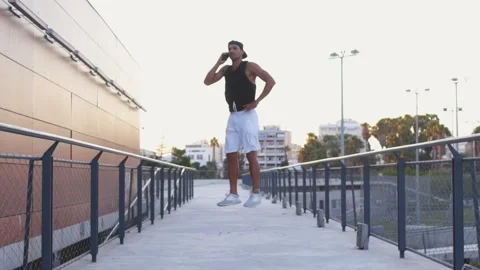 Young hipster man jumping high on air and talking on mobile phone Stock Footage 132070381