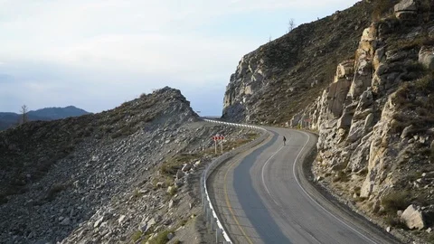 Young hipster man rides longbord or skateboard down beautiful mountain road. Stock Footage 103141153