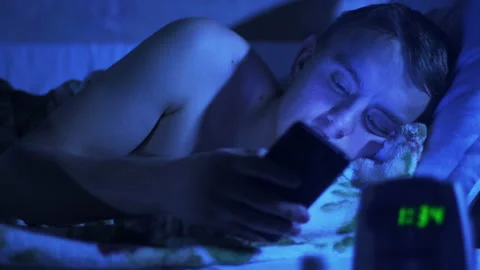 Young Hipster Man using a Smartphone Lying on Bed at Home Late at Night Stock Footage 124022315