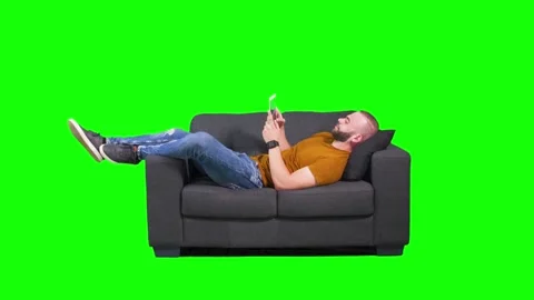 Young hipster man using tablet while lying down on sofa Stock Footage 136370124