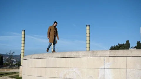 Young hipster man walking on the wall in sunny day Stock Footage 106727096