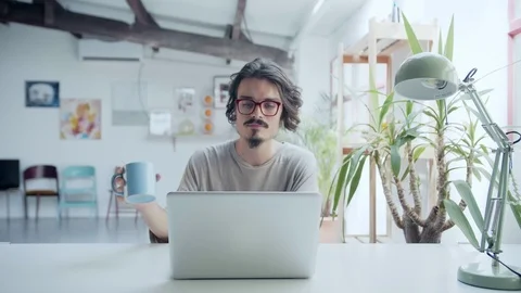 Young hipster working on computer and relaxing drinking a cup of tea or coffee Stock Footage 98896038