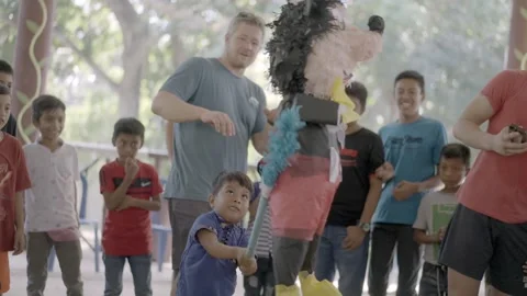 Young hispanic boy hitting pinata at party in guatemala Stock Footage 234142282