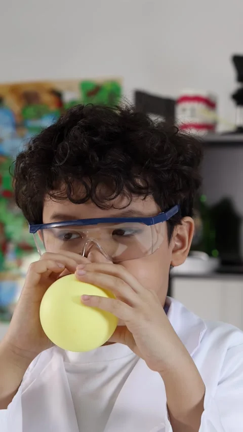 Young Hispanic Boy in Lab Coat Blowing Up Yellow Balloon Видео 338155556