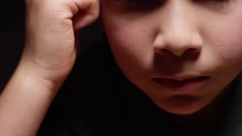 Young hispanic boy sitting at desk in the dark depressed, frustrated, scared Stock Footage 141758341