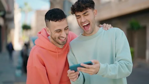 Young hispanic couple smiling confident watching video on smartphone at stree Stock Footage 171791663