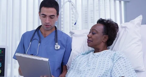 Young hispanic doctor reviewing health history with senior African patient Stock Footage