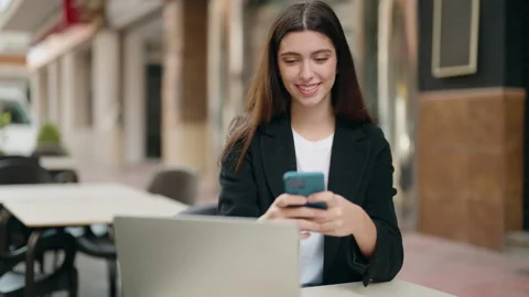 Young hispanic girl using laptop and smartphone at coffee shop terrace Video stock 170633740