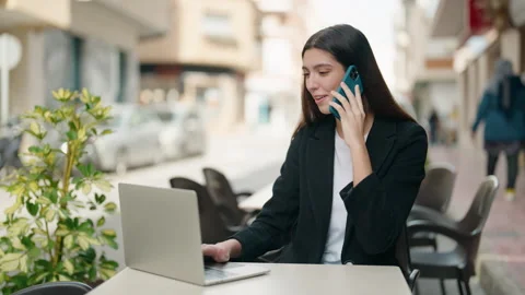 Young hispanic girl using laptop and talking on the smartphone at coffee shop Video stock 171382637