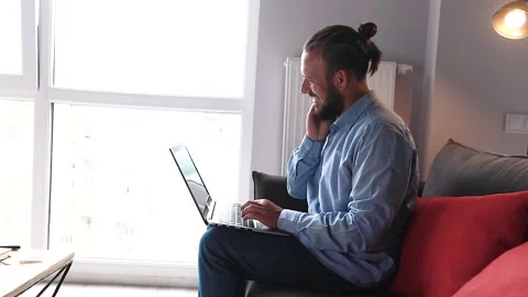 Young hispanic guy sitting on the couch and typing a message on a laptop Stock Footage 136626061