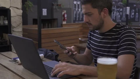 Young hispanic male using mobile and computer in office bar Stock Footage 153292712