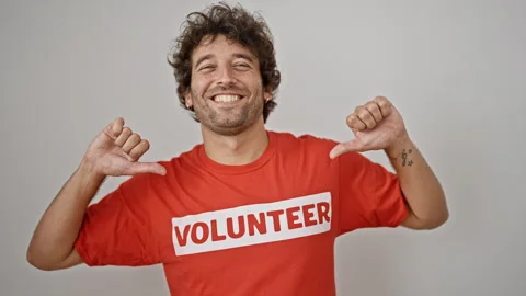 Young hispanic man activist pointing to volunteer uniform smiling over isol.. Video stock 247379113