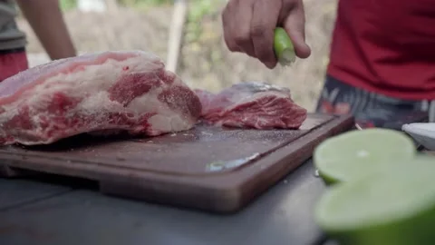 Young hispanic man adds lemon to a piece of barbecue meat Stock Footage 172441467