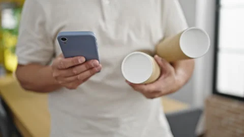 Young hispanic man architect using smartphone holding blueprints at office Video stock 245023550