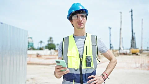 Young hispanic man architect using smartphone at construction place Video stock 247384895
