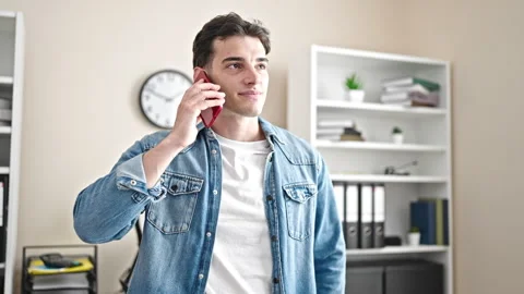 Young hispanic man business worker talking on smartphone working at office Video stock 243481427