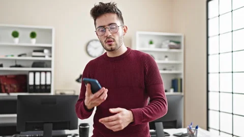Young hispanic man business worker talking on smartphone working at office Video stock 245044507