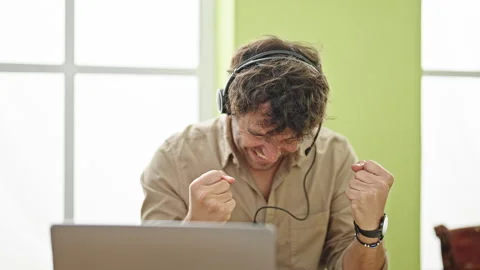Young hispanic man business worker using laptop and headphones celebrating .. Stock Footage 245045389