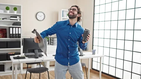 Young hispanic man business worker holding coffee and clipboard dancing at .. Video stock 247378325