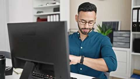 Young hispanic man business worker using computer looking at the time celeb.. Video stock 247906641