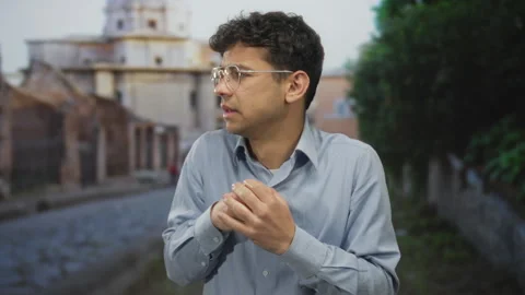 Young hispanic man clasping hands on narrow cobblestone street in old town;.. 스톡 동영상 315083434