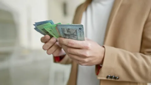 Young hispanic man counts malaysian ringgit on city street, blurring urban .. Stock Footage 272186840
