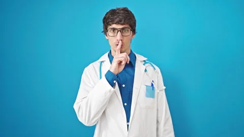 Young hispanic man doctor asking for silent over isolated blue background Video stock 247385004