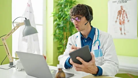 Young hispanic man doctor doing video call with laptop writing on touchpad .. Video stock 247385020