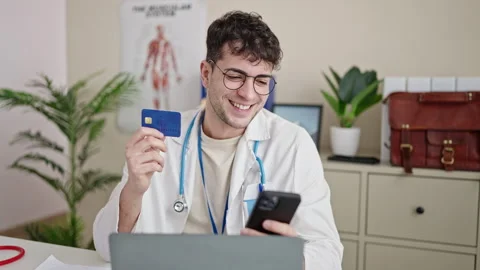 Young hispanic man doctor using smartphone working doing online shopping at.. Stock Footage 243484412