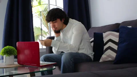 Young hispanic man doubting whether or not to buy with his credit card online Video stock 142845505