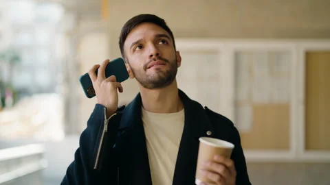 Young hispanic man drinking coffee listening audio message by the smartphone  Video stock 170655333