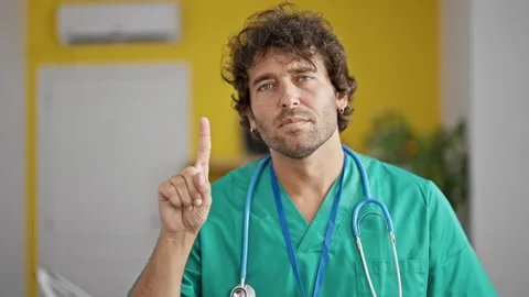 Young hispanic man drinking coffee using laptop at clinic Stock Footage 245558579
