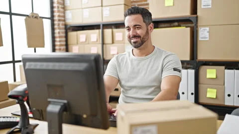 Young hispanic man ecommerce business worker using computer smiling at office Stock Footage 245080098