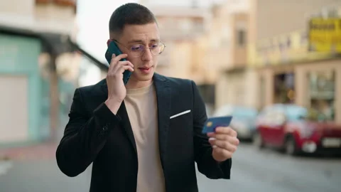 Young hispanic man executive talking on the smartphone holding credit card at Video stock 172054074