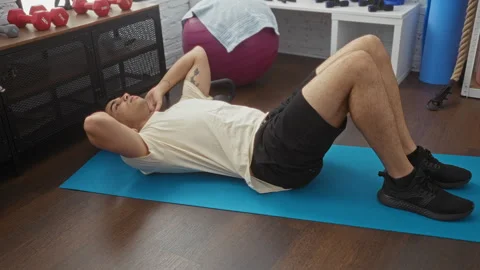Young hispanic man exercising indoors, performing abdominal crunches on a b.. Stock Footage 285095423