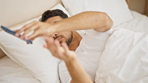 Young hispanic man finishing to use smartphone to sleep at bedroom Video stock 246127064