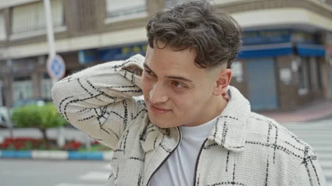 Young hispanic man with hand on neck wearing white check jacket on urban st.. Stock Footage 337423882