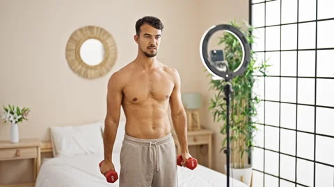 Young hispanic man having online training with dumbbells at bedroom Stock-Footage 246127123