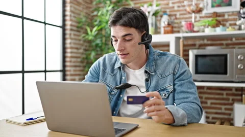 Young hispanic man having video call holding credit card at dinning room Video stock 246123596